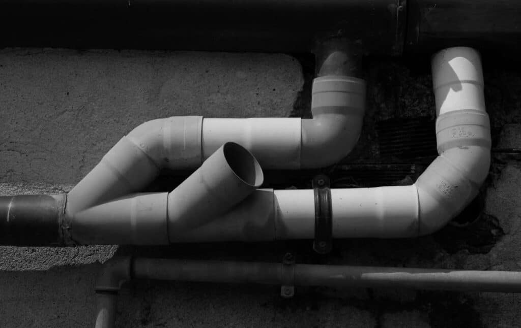 interconnected PVC pipes mounted on an exterior wall.