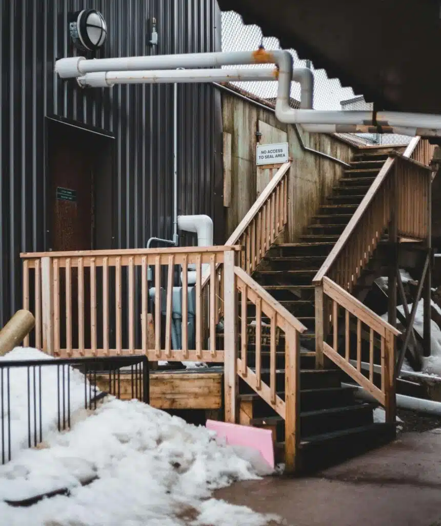 Insulated outdoor pipes near a staircase, demonstrating the importance of pipe insulation in preventing freezing.