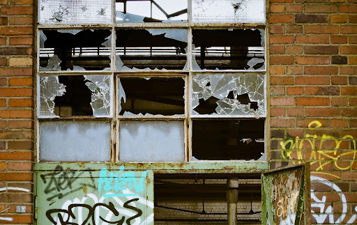 Broken windows in an abandoned building with graffiti, representing the type of damage typically involved in vandalism claims.