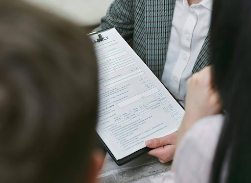 Close-up of an insurance agent reviewing a claim form with clients, illustrating the claim review process.