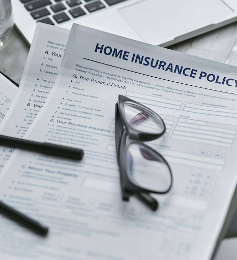 A close-up of a homeowners insurance policy document with glasses on top.