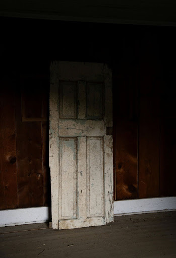 A weathered, unused door leaning against a wall, symbolizing the risk of deterioration in unoccupied properties.