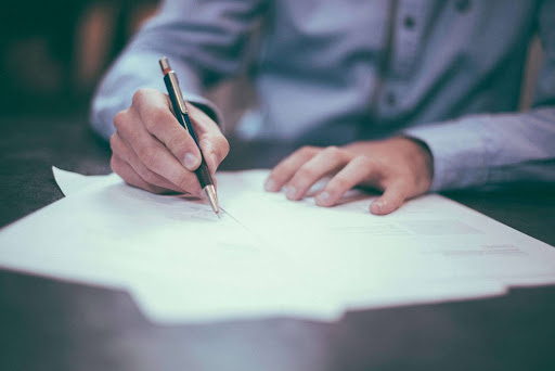 A close-up of a person signing home insurance paperwork, representing the importance of insuring unoccupied homes.