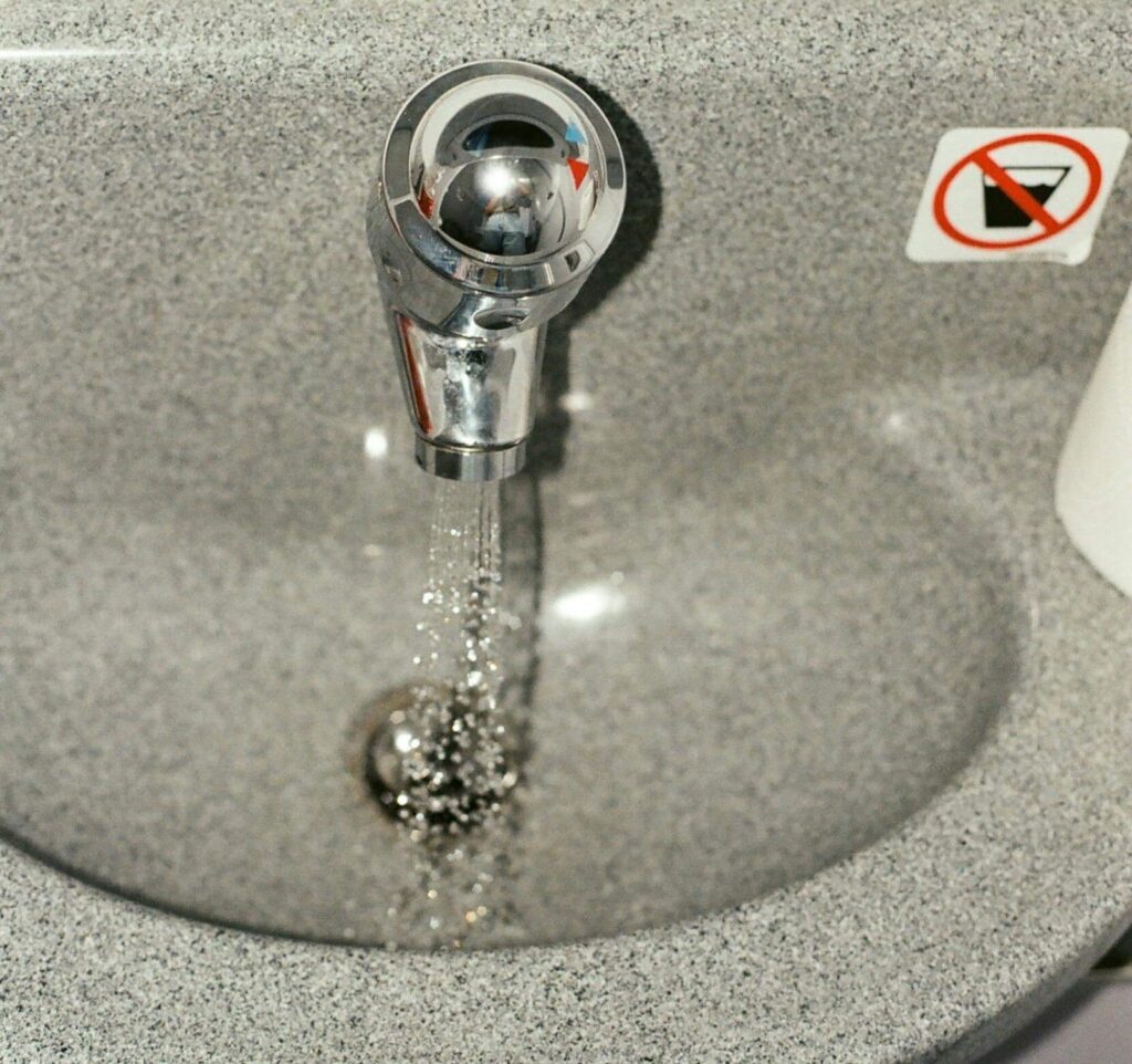 Water flowing from a faucet in a sink, illustrating potential water overflow from clogged drains.