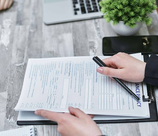 Close-up of a person signing a water damage insurance policy, highlighting protection against plumbing issues.