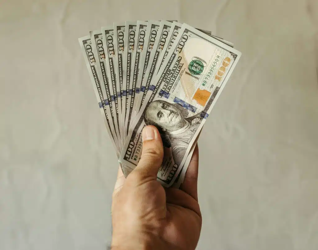 A white male hand holding up several dollar bills.