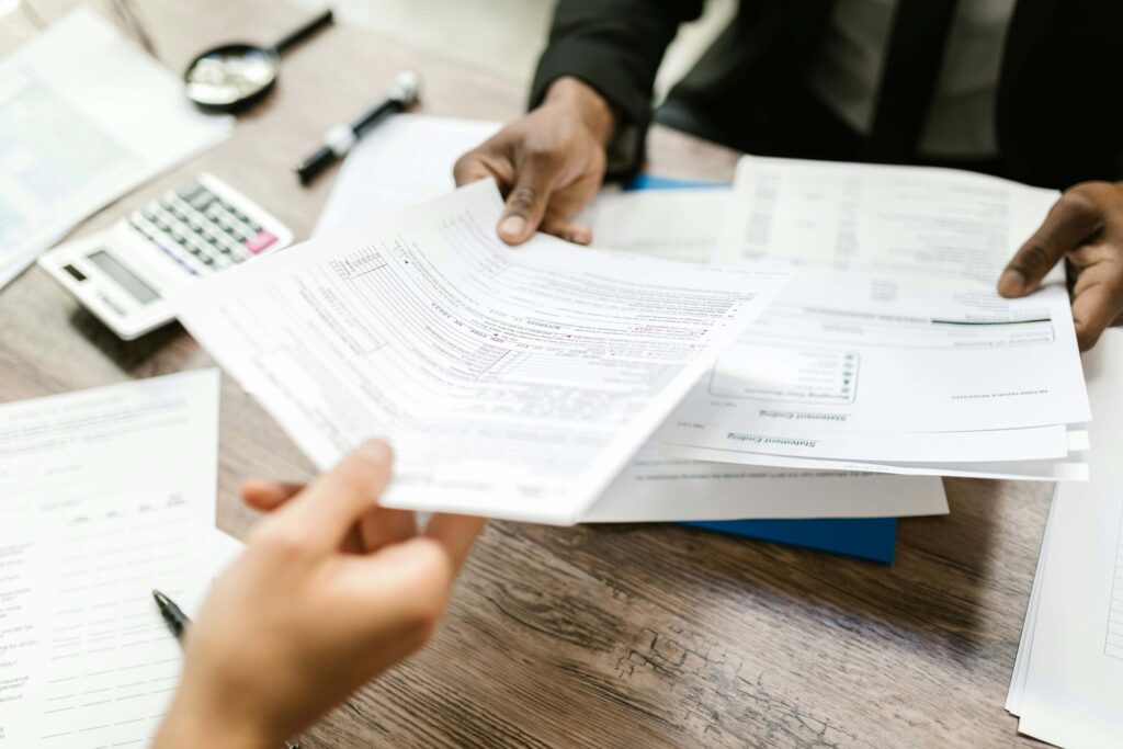 A man handing blurred documents to another person