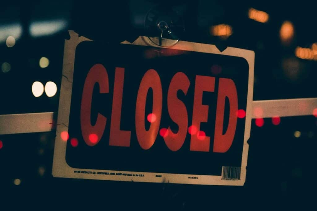 A black and white sign with the word “CLOSED” printed on it.