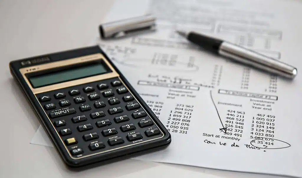 A black calculator and pen resting on a financial report.