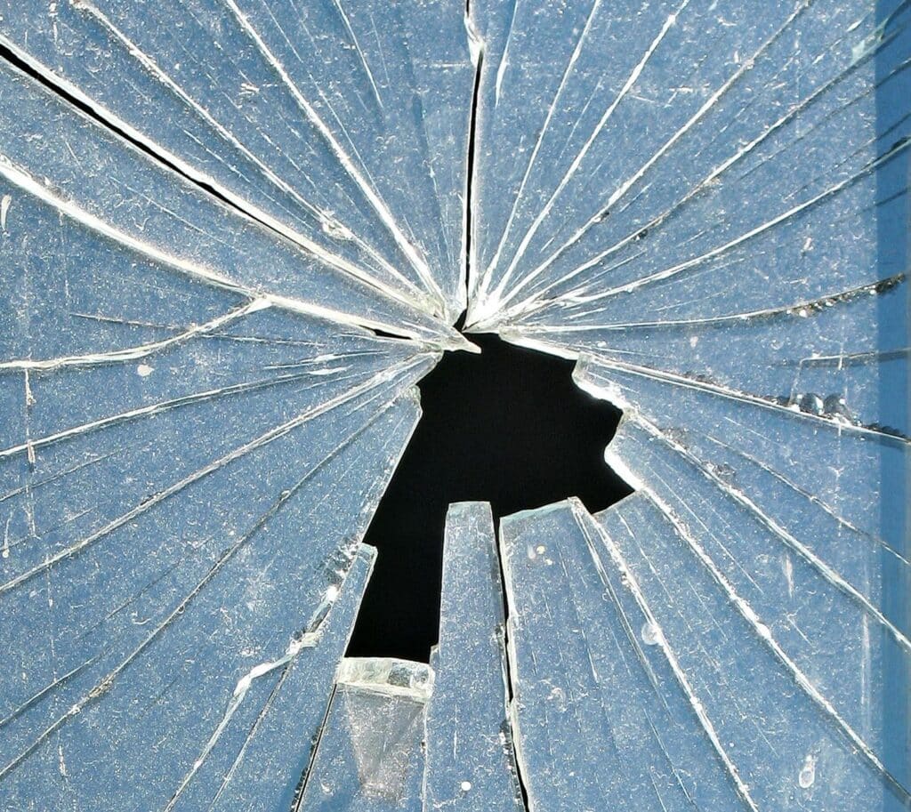 A cracked window glass with a jagged hole in its middle.