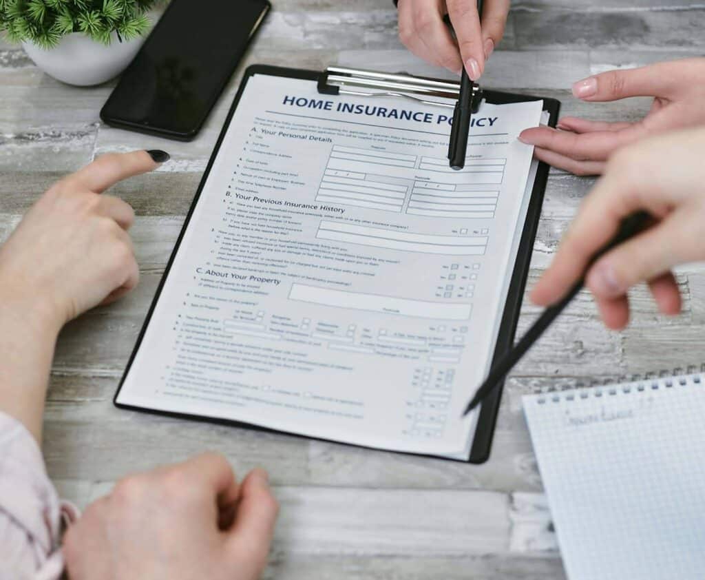 Three people pointing to a home insurance policy document.