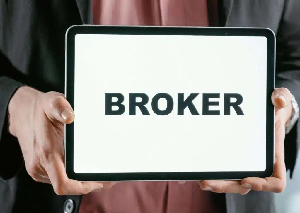 A man holding a tablet with ‘broker’ written on it.