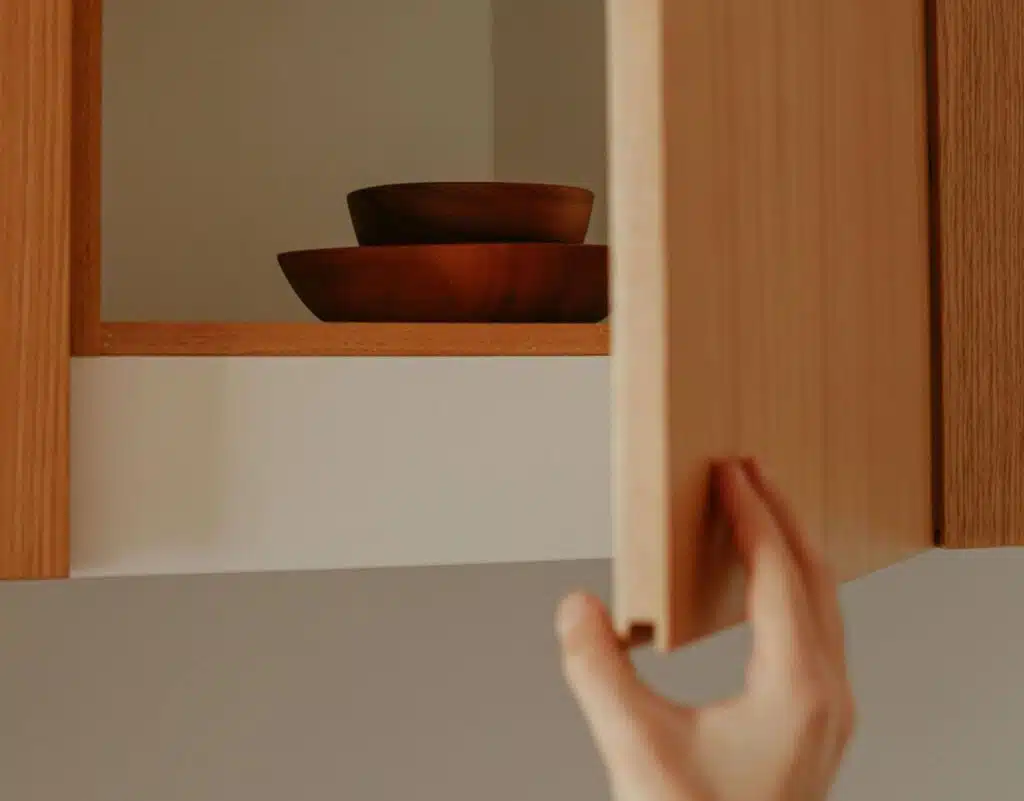 An open kitchen cabinet with two wooden bowls in it.