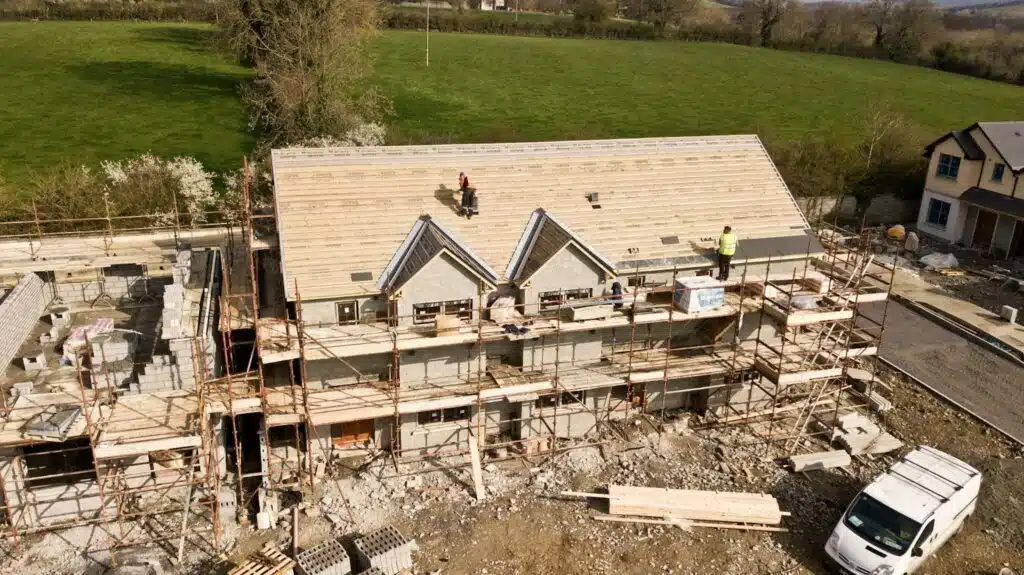 A mansion under construction with multiple contractors working on it.