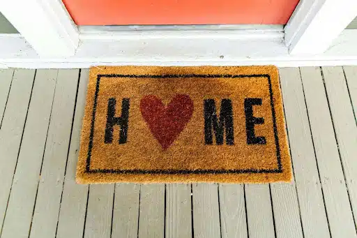 A yellow doormat with “HOME” printed on it. The ‘O’ is a heart.