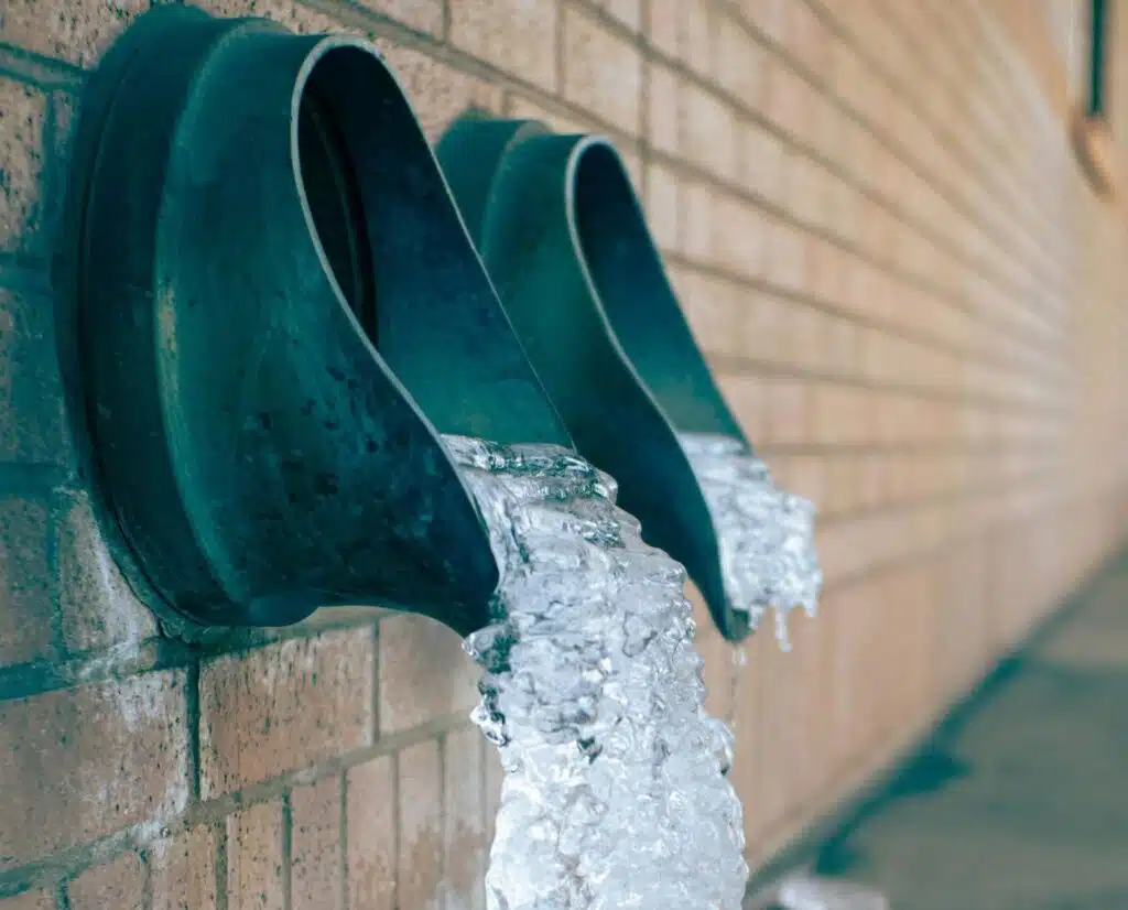 Ice spilling out of pipes in the wall.