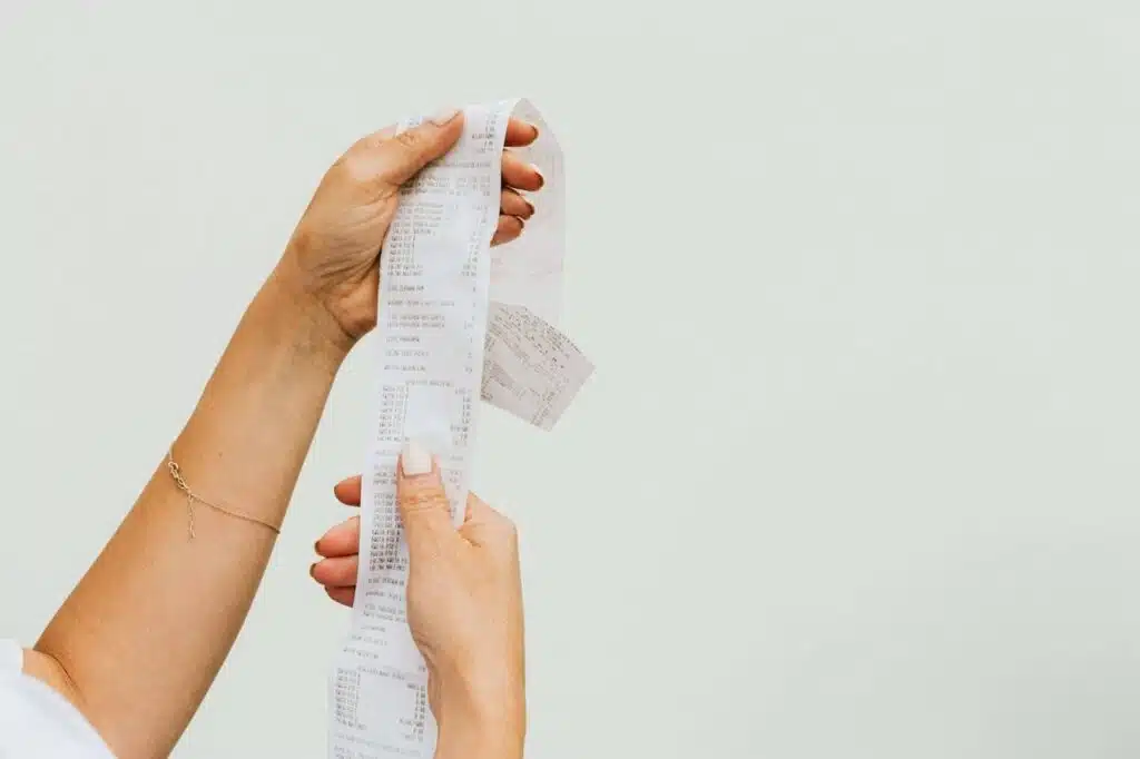 A person holding up a long receipt.